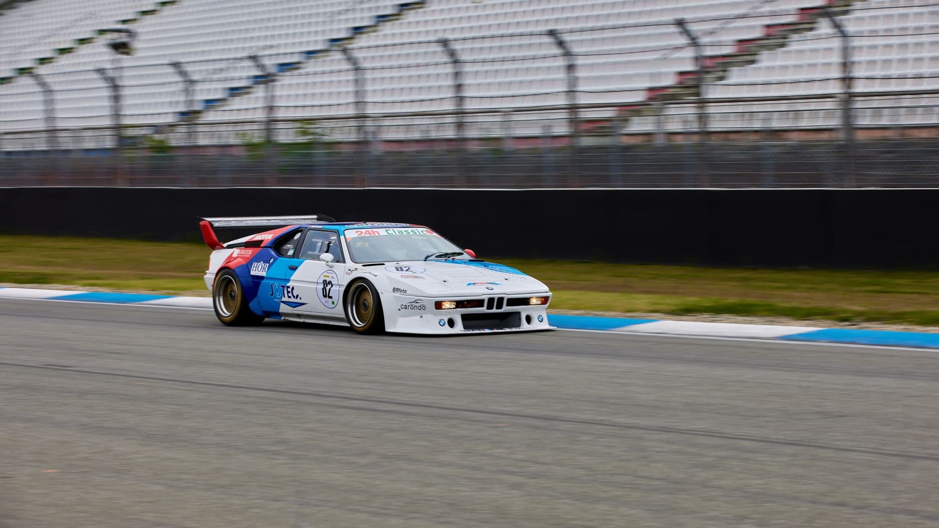Classic BMW racing car speeding on a racetrack, showcasing motorsport enthusiasm.
